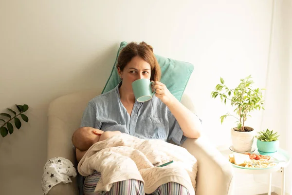 Woman drink tea or coffee during process of breastfeeding of newborn baby — Stock Photo, Image