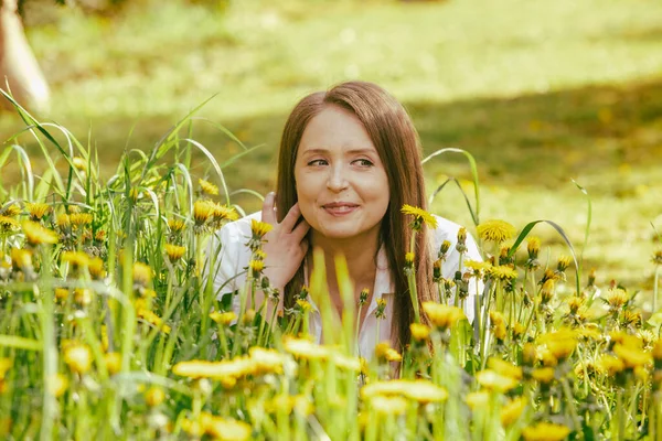 Smiling woman lying at the dandelion field — Stock Photo, Image