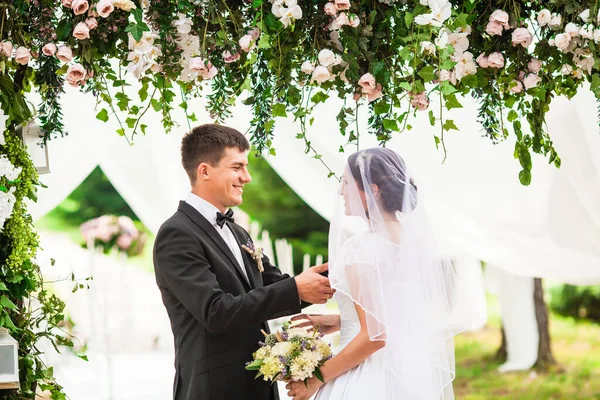 結婚式で花のアーチの下の結婚式のカップル — ストック写真