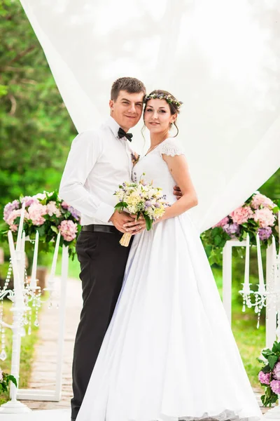 Casal de casamento sob o arco de flores na cerimônia de casamento — Fotografia de Stock