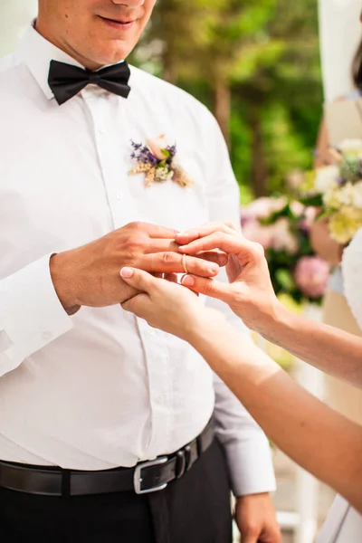 Bruidspaar onder de bloemboog tijdens de huwelijksceremonie — Stockfoto