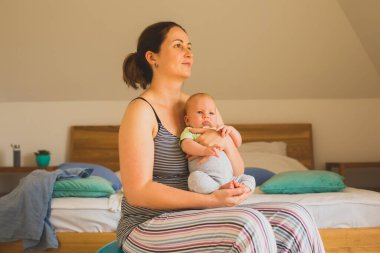 Anne kucağında ve sallanan bebek Fitball 'da oturuyor