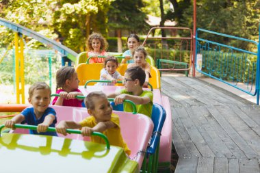 Lunaparktaki lunaparkta hız trenindeki mutlu çocuklar.
