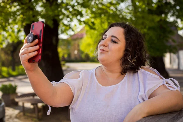 Усміхнена жінка на вулиці використовує мобільний і має відеодзвінок . — стокове фото