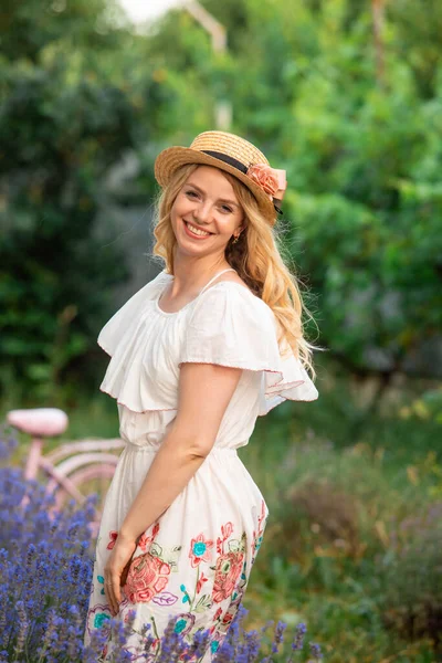 Красивая блондинка в шляпе возле кустов лаванды — стоковое фото