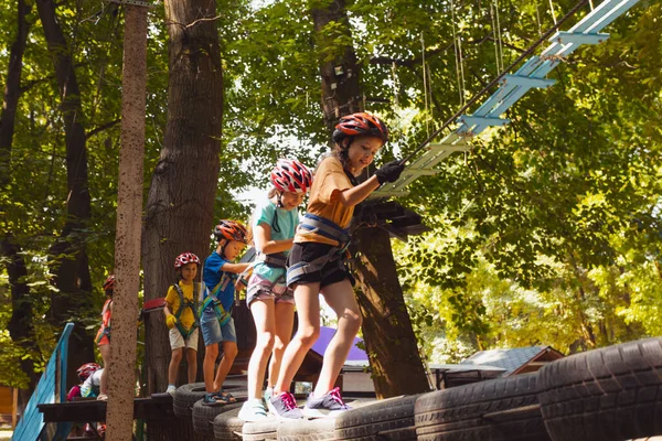 De kinderen overwinnen obstakels in het touwenpark. — Stockfoto