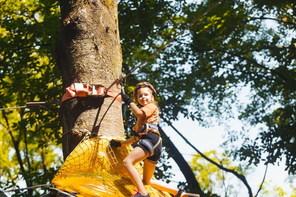 Концентрированная девушка осторожно преодолевает препятствия в веревочном парке — стоковое фото