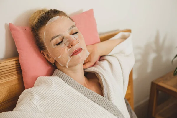 The young woman relaxes with skincare face mask