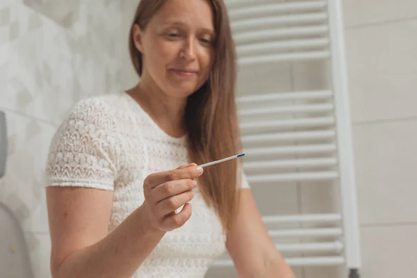 Középkorú nő terhességi teszttel a mosdóban — Stock Fotó