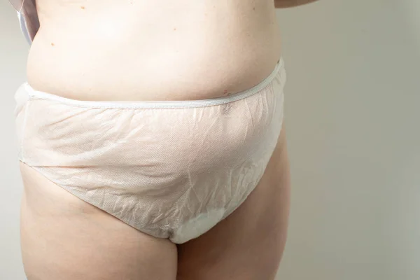 Female postpartum belly in disposable underpants, hygiene