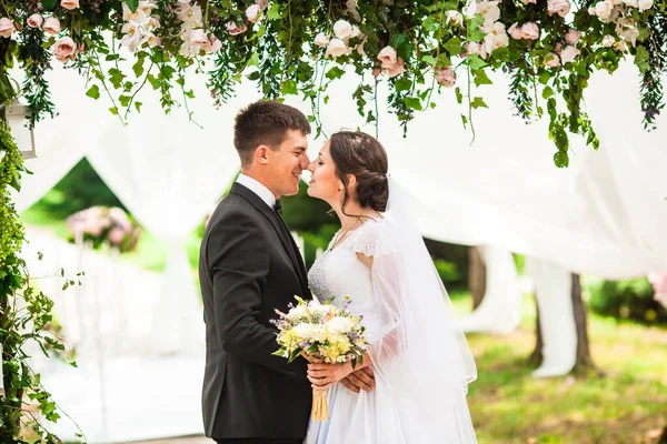 Γάμος ζευγάρι κάτω από την καμάρα λουλουδιών στην γαμήλια τελετή — Φωτογραφία Αρχείου