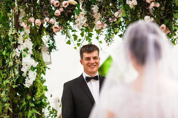 Pareja de boda bajo el arco de flores en la ceremonia de boda —  Fotos de Stock