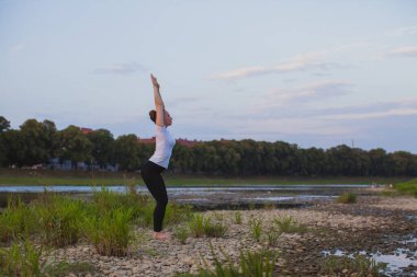 Genç kadın doğada kayalar üzerinde yoga yapıyor.