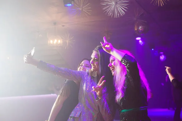 Grupo de amigos tomando selfies en un teléfono móvil en una discoteca —  Fotos de Stock