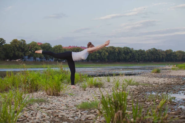 Ung kvinna gör yoga på stenar i naturen — Stockfoto