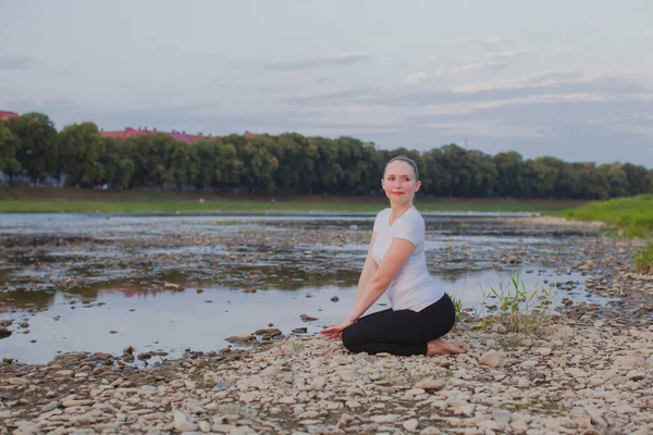 Ung kvinna gör yoga på stenar i naturen — Stockfoto