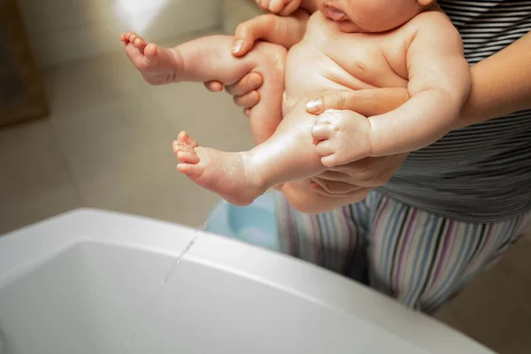 Mother washes her baby after stool at the shower — Stock Photo, Image