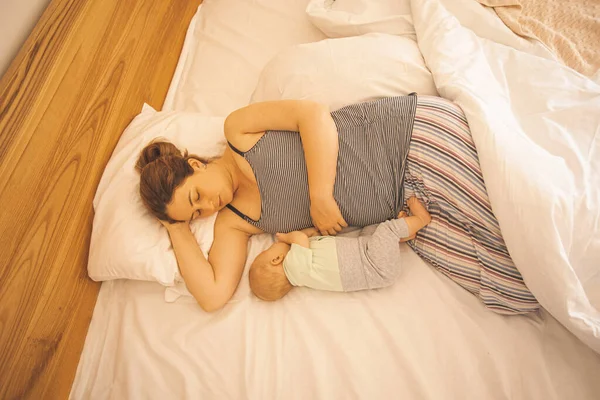 Moeder en pasgeboren baby slapen in bed — Stockfoto