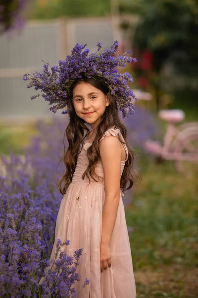 庭でラベンダーの茂みの近くの美しい長い髪の女の子 女の子は花から花輪を作った — ストック写真