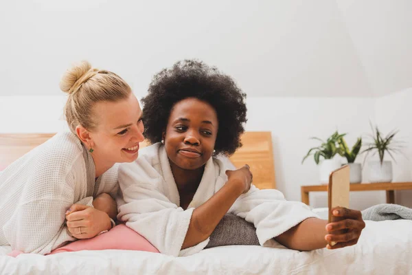 Δύο Νεαρές Γυναίκες Είναι Ξαπλωμένες Στο Κρεβάτι Και Βγάζουν Σέλφι — Φωτογραφία Αρχείου
