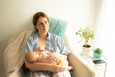 Genç anne yeni doğmuş bebeğini emzirmek istiyor ama göğüs ağrısı çekiyor.