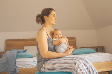 Anne kucağında ve sallanan bebek Fitball 'da oturuyor. Yatak odasında uyuyan yeni bir bebek ile yeni bir yaşam tarzı