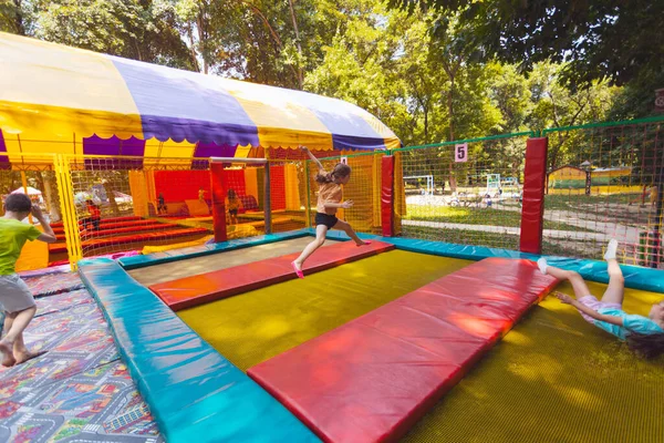 The young children are jumping in the bright trampoline park outdoors in the summer park