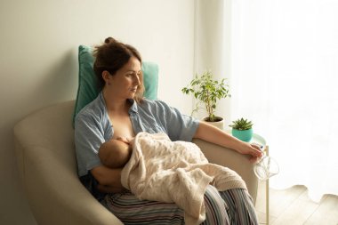 Bir kadın yeni doğan bebeği emzirme işlemi sırasında su içer. Rahat ve destekli emzirme