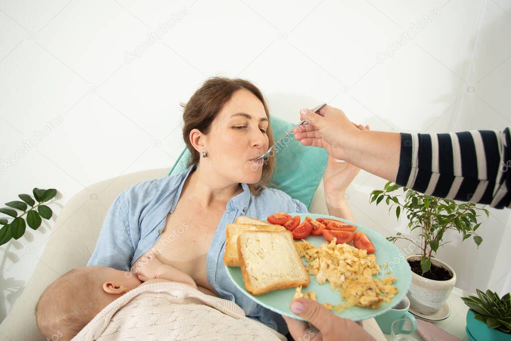 Elder woman helps to eat for new mother when she breastfeeds her baby. Motherhood support