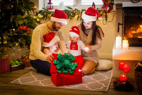 クリスマスの時間に暖炉の近くの木の近くに魔法の贈り物を持つ幸せな家族の母親と子供 — ストック写真