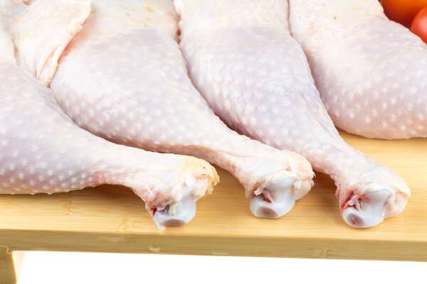 Fresh raw chicken wings on chopping board with roma tomatoes