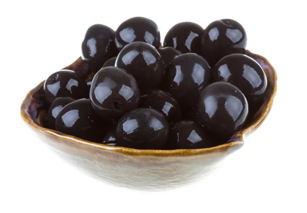 Оливки чорні, политі оливковою олією в мисці ізольовані на білому — стокове фото