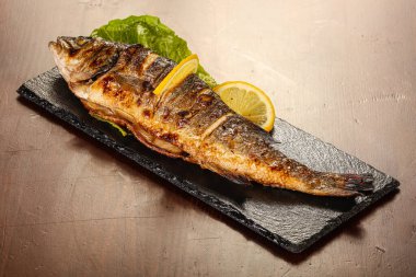 Izgara deniz kabuğu limon dilimi ve salata yaprakları servis edilir.