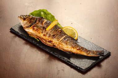 Izgara deniz kabuğu limon dilimi ve salata yaprakları servis edilir.