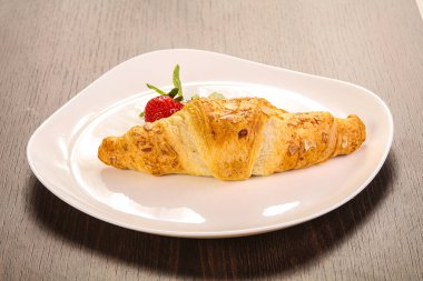 Tatlı kruvasan tabakta çilek servis edilir.