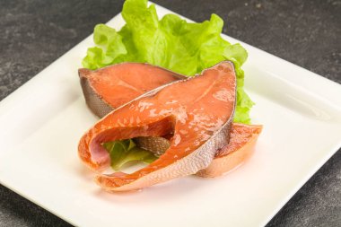 Salata yapraklarıyla servis edilen iki pembe somon balığı bifteği.