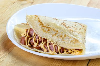 Dilimlenmiş sosis ve hardal soslu krep.