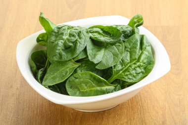 Tahta arka planda taze yeşil ıspanak yaprakları var.