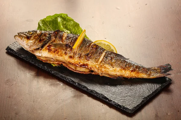 Izgara deniz kabuğu limon dilimi ve salata yaprakları servis edilir.