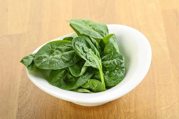 Tahta arka planda taze yeşil ıspanak yaprakları var.