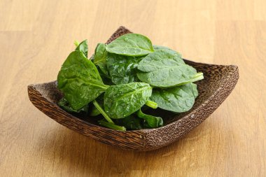 Tahta arka planda taze yeşil ıspanak yaprakları var.