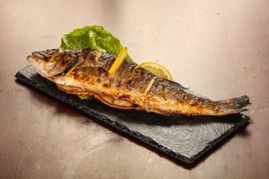 Izgara deniz kabuğu limon dilimi ve salata yaprakları servis edilir.