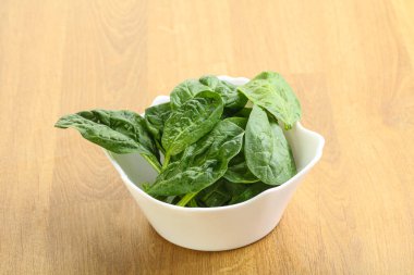 Tahta arka planda taze yeşil ıspanak yaprakları var.