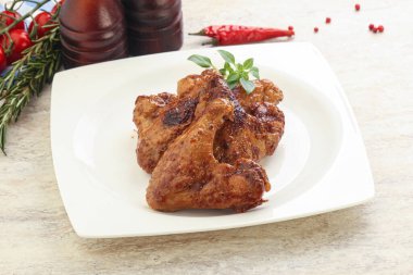 Baharatlı soslu kızarmış tavuk kanadı. Fesleğen yaprağı.