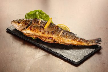 Izgara deniz kabuğu limon dilimi ve salata yaprakları servis edilir.