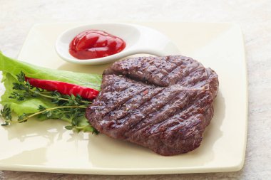 Izgara pala etekli biftek kekik ve ketçap servis edilir.