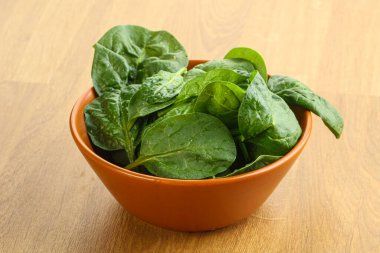 Tahta arka planda taze yeşil ıspanak yaprakları var.