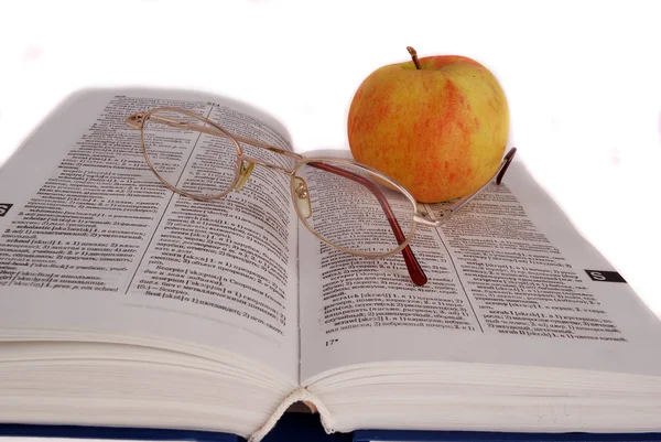 Яблоко и очки на книге — стоковое фото