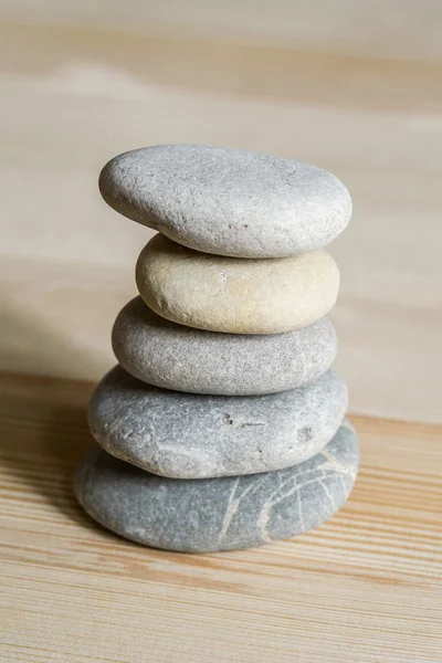 Five spa zen stones stacked on a wood background