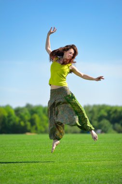 genç kadın bir yeşil çayır üzerinde atlama